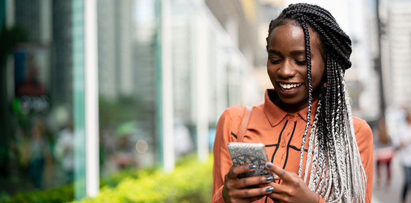 woman smiling while using her mobile phone