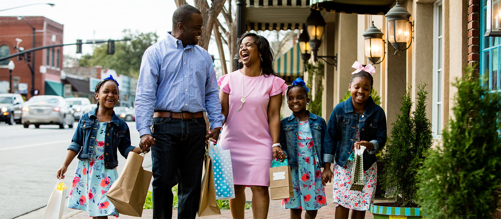 a family smiling and walking down main street